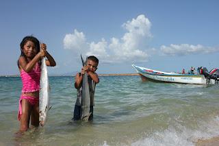 Photographie d'enfants tenant des poissons sur une plage